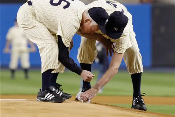 Whitey Ford (left) helps Don Larsen (right) scoop up dirt from the pitcher's mound